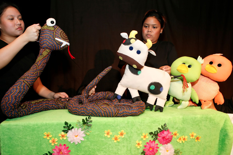 The cow protecting the duck puppets against the snake in Duckie Can't Swim by Paper Monkey Theatre