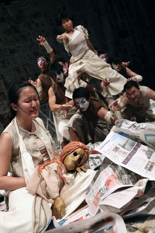 Group of actors pointing to a female puppet lying down