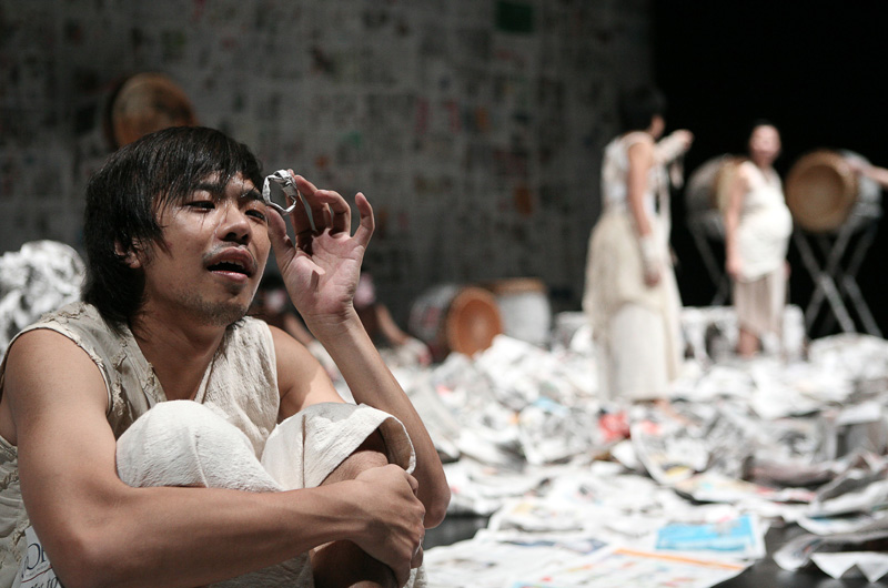 The Hero looking at a ring made of newspaper in Death of A Hero by Paper Monkey Theatre Singapore