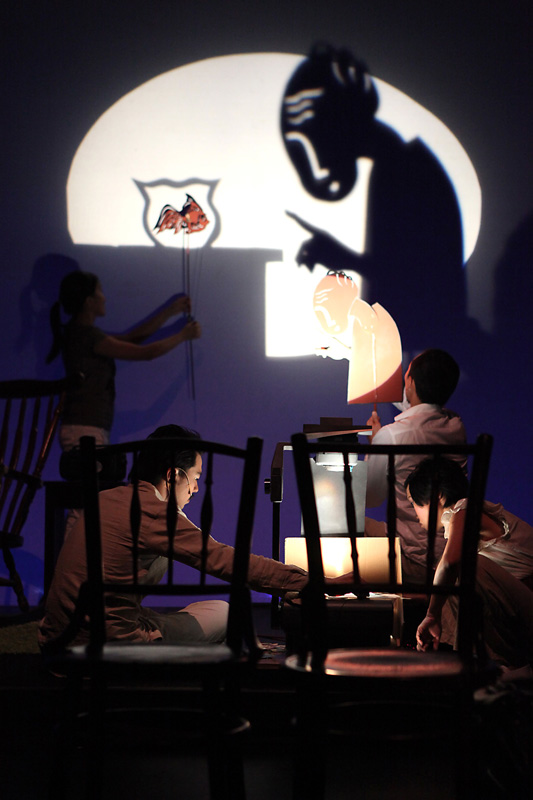 Two chairs on foreground and shadow puppet projected on background in Home Boxes