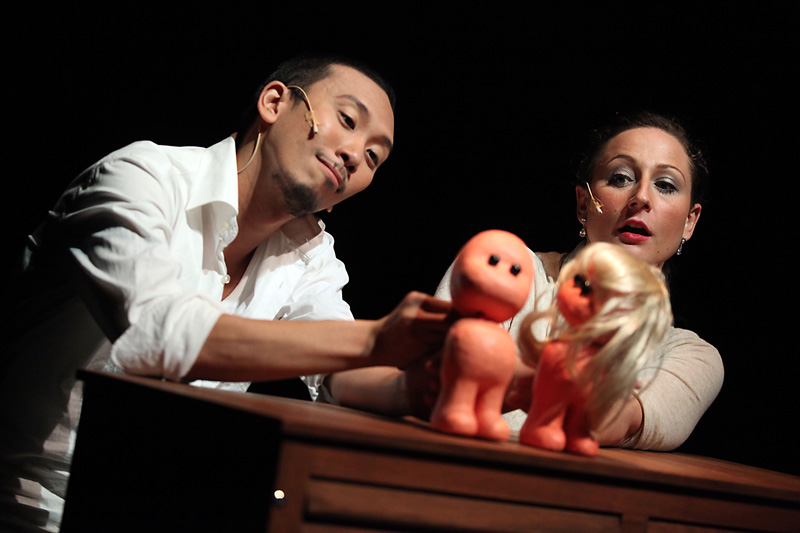 Two actors on stage holding puppet dolls