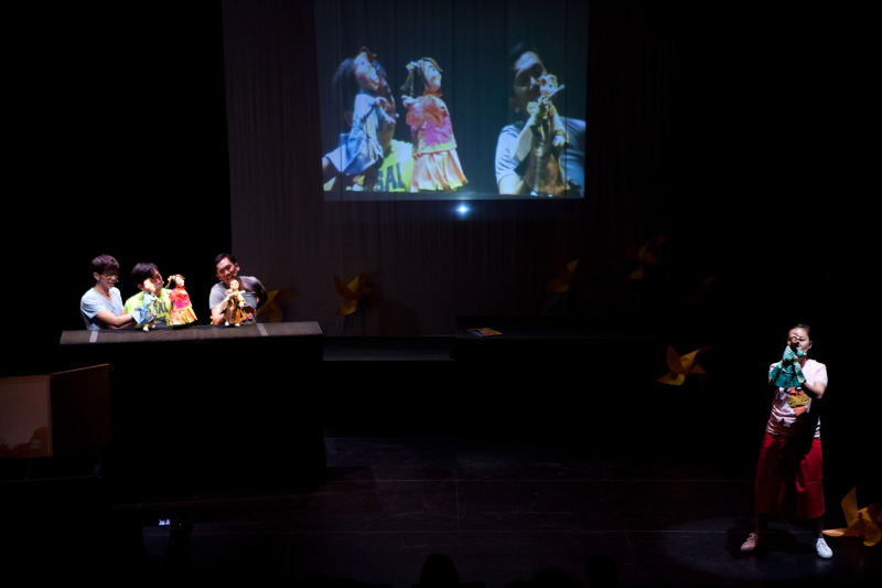 Actors manipulating hand puppets with projection on screen in The Three Big Bullies by Paper Monkey Theatre Singapore