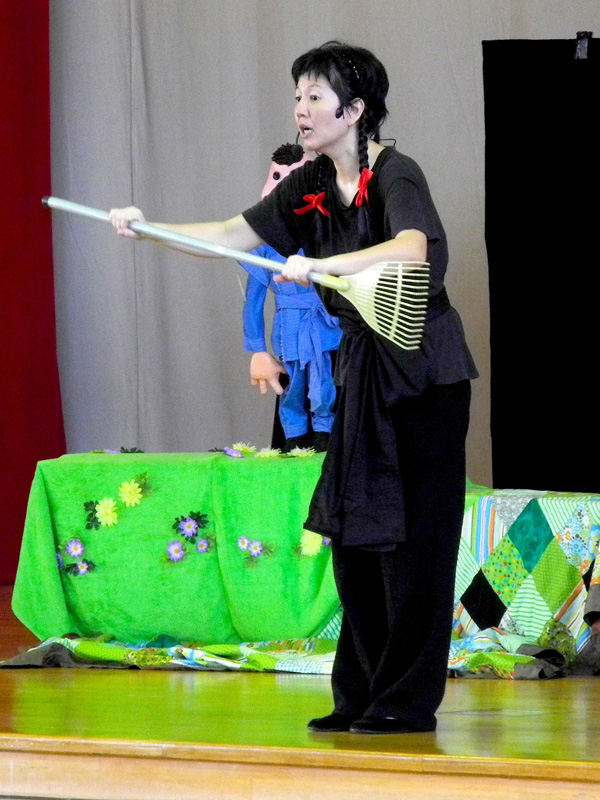 An actress holding a prop broom in Dragon Dance Community Tour by Paper Monkey