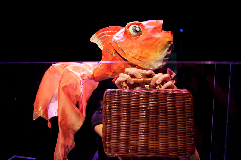 Gold fish puppet holding a luggage in Goldfish, Go Fish by Paper Monkey