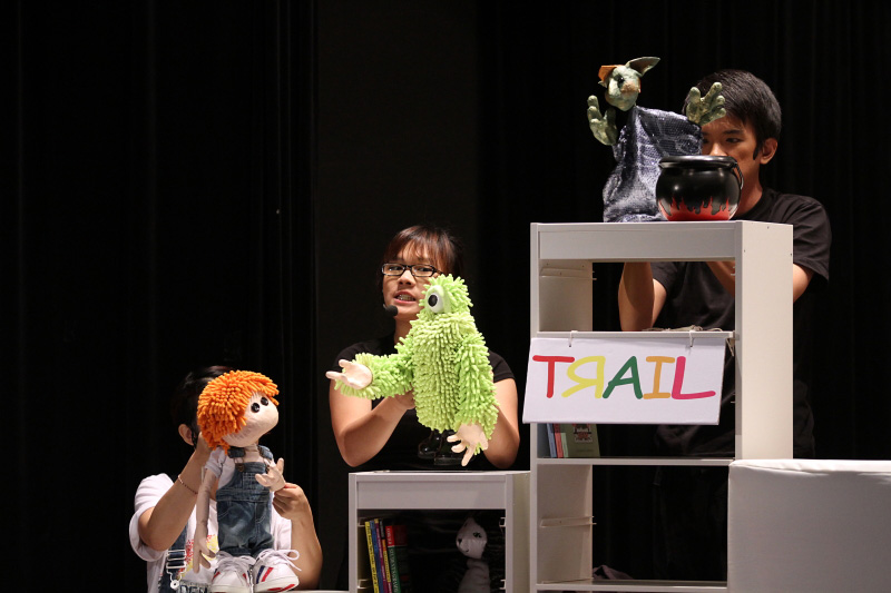 Green monster and puppet Joey learning with another witch puppet on top in Monster Under My Bed by Paper Monkey