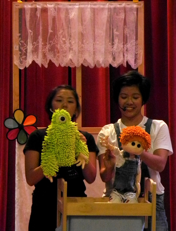 Joey puppet and green monster puppet waving in Monster Under My Bed Community Tour
