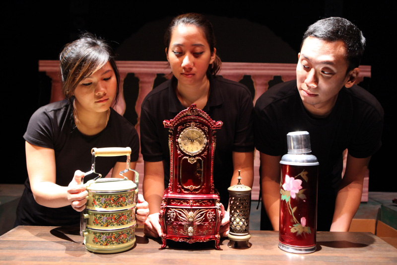Old clock, hot water flask and tingkat in Three colourful nonya puppets with flowers in The Nonya Nightingale by Paper Monkey Theatre Singapore