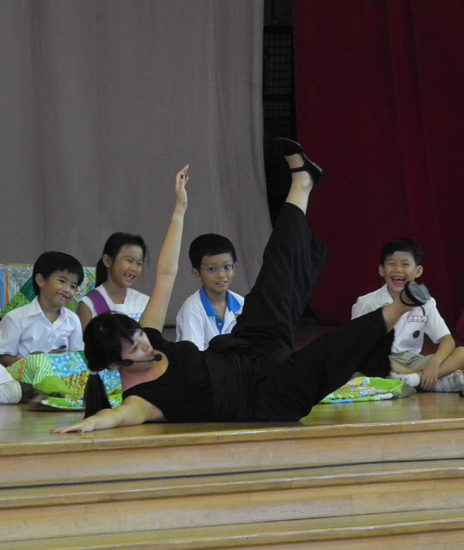 Student audience with an actress falling in front of them in Dragon Dance Community Tour by Paper Monkey