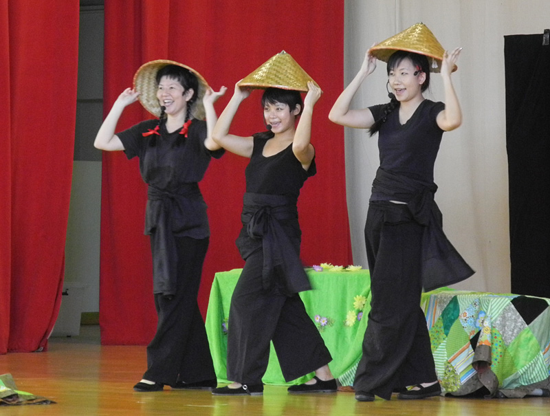 Three actors holding straw hats in dance pose in Dragon Dance Community Tour by Paper Monkey