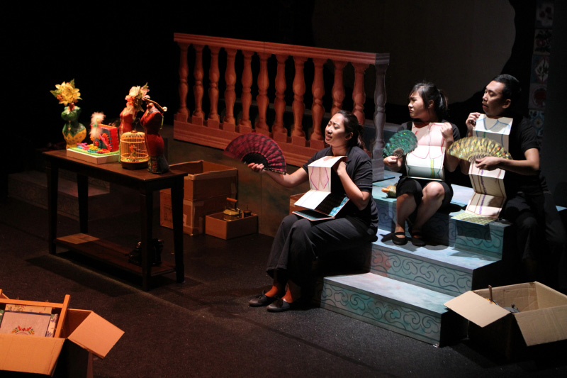 Three actors with paper Nonya costumes sitting on steps in The Nonya Nightingale by Paper Monkey Theatre Singapore