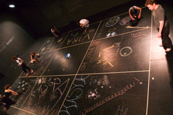 nine squares drawn on a black floor with chalk scribbles