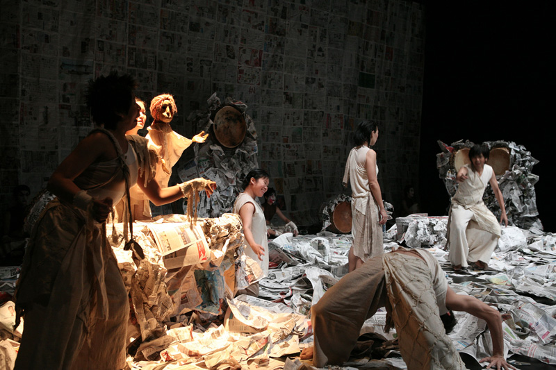 Actors on newspaper set and a puppet in Death of A Hero by Paper Monkey Theatre Singapore
