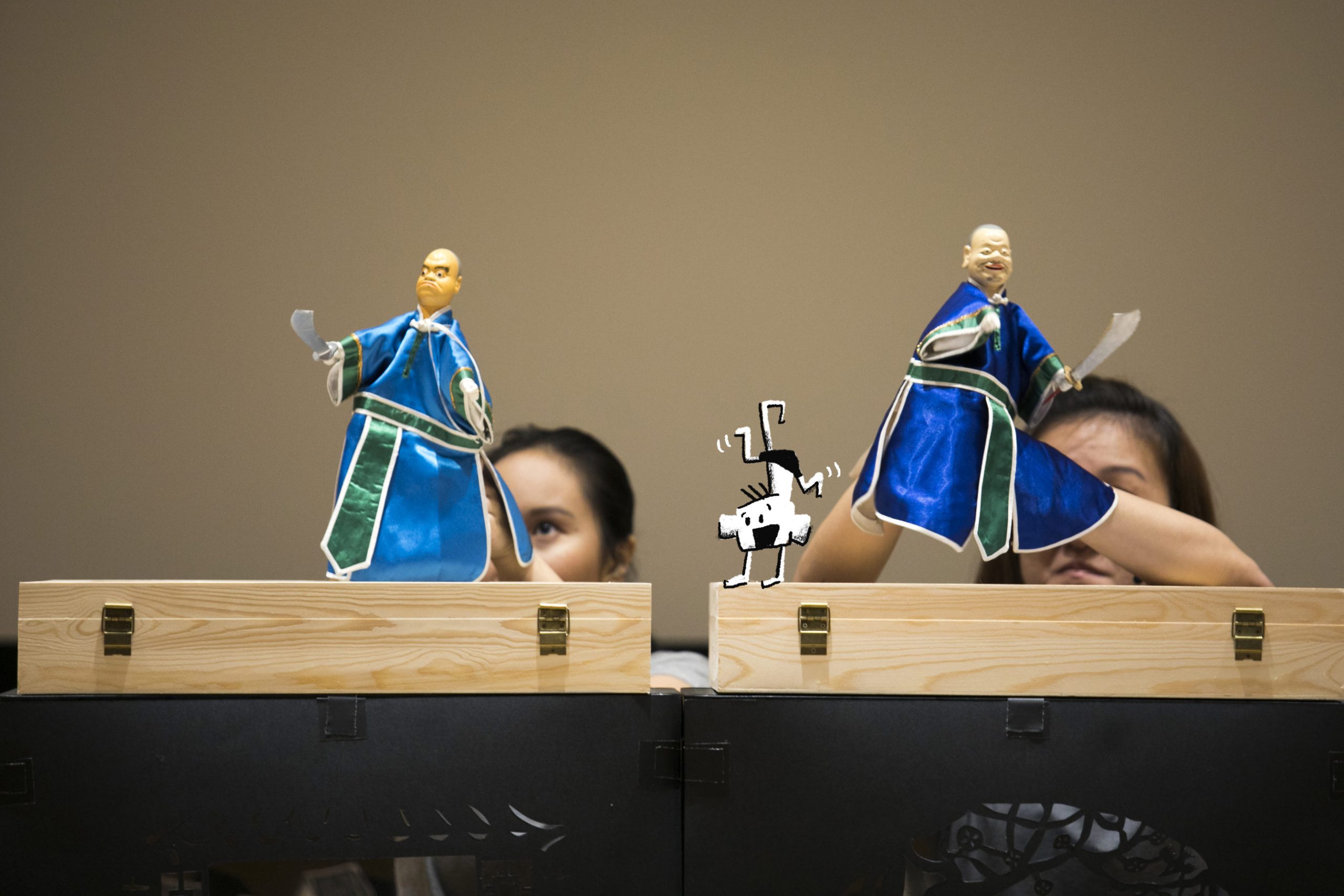 Two traditional hand puppets with swords on hand manipulated by puppeteers