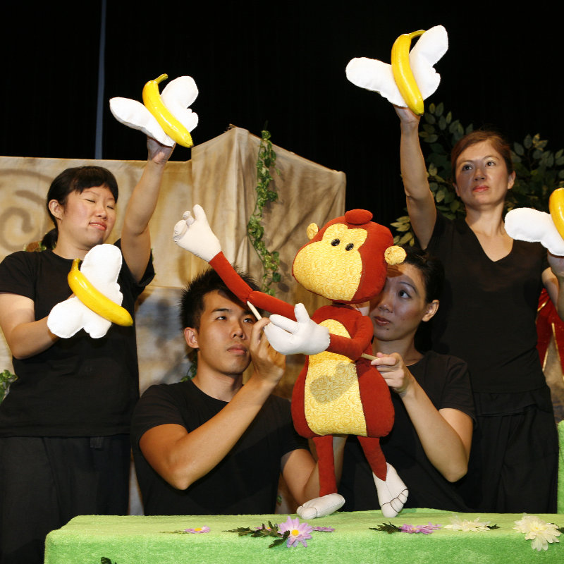 A monkey puppet singing towards flying bananas with butterfly wings