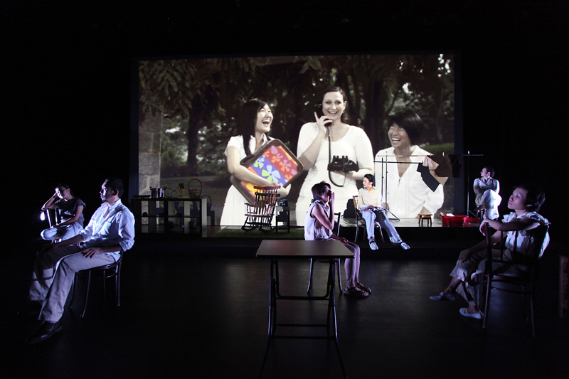 Actors on stage with video projected in the background in Home Boxes
