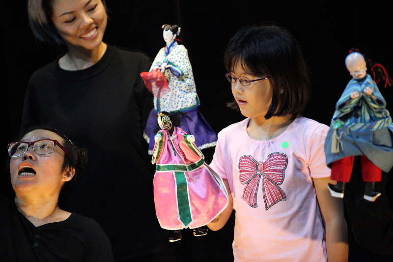 A girl audience holding traditional hand puppet At Treehouse The Three Big Bullies by Paper Monkey Theatre