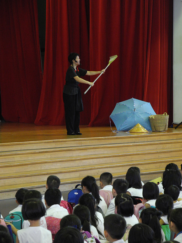 An actress holding a prop in front of student audience in Dragon Dance Community Tour by Paper Monkey