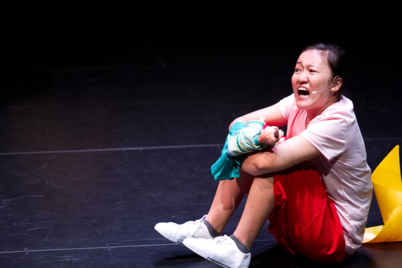 An actress holding hand puppet sitting down in The Three Big Bullies by Paper Monkey Theatre Singapore