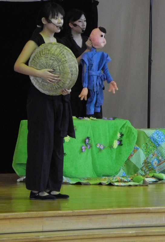 Boy puppet with an actress holding a straw hat in Dragon Dance Community Tour by Paper Monkey