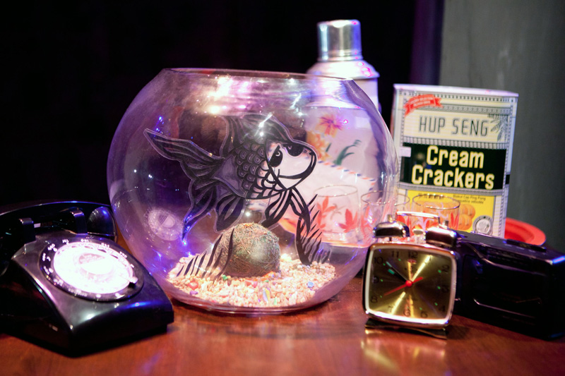 Close up of old phone gold fish tank and flask in Goldfish, Go Fish by Paper Monkey
