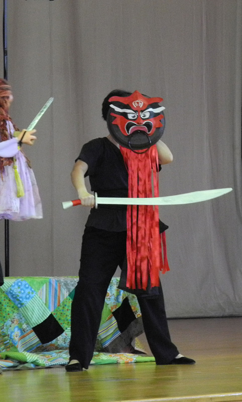 Monster puppet with red mask holding a sword prop in Dragon Dance Community Tour by Paper Monkey