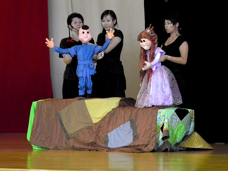 Princess life size puppet with boy puppet hands opened wide in Dragon Dance Community Tour by Paper Monkey