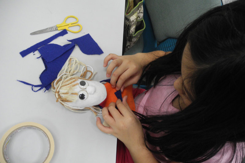 A little girl learning how to make puppets